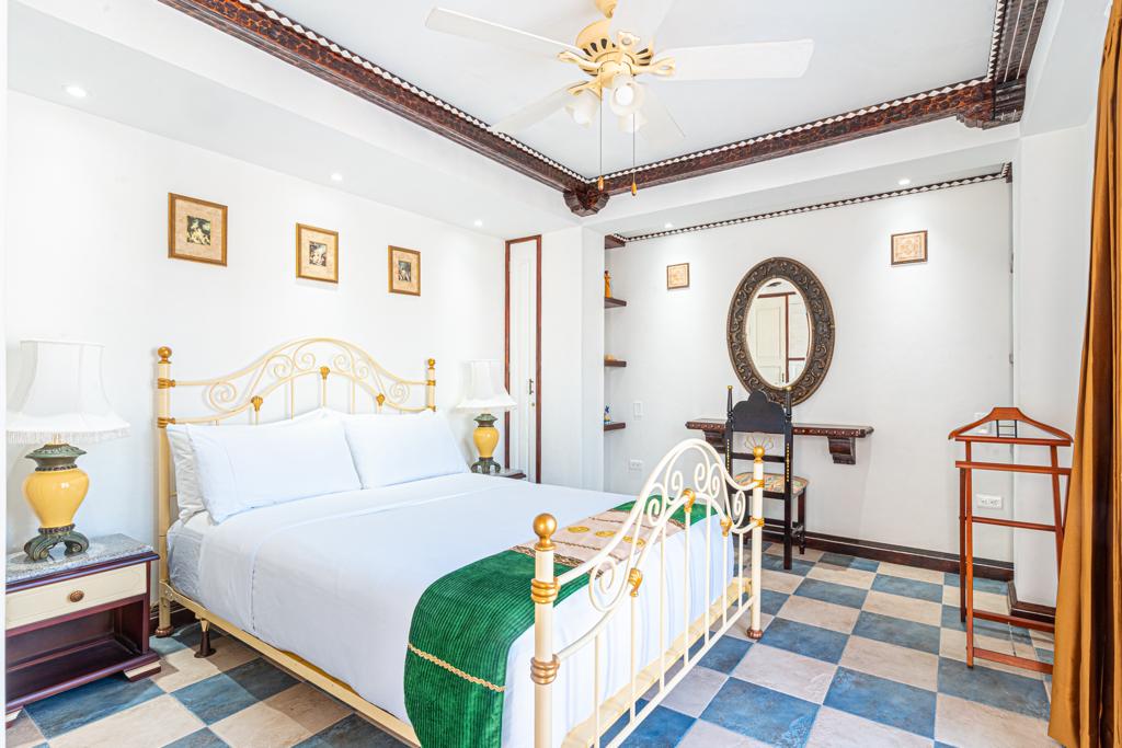 Habitación con cama de bronce y cubrecama verde